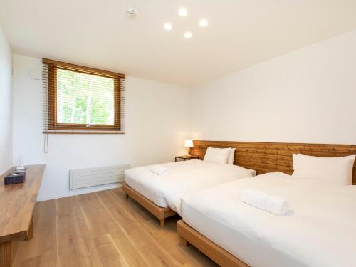 新雪谷的住宿－Birchwood Chalet，一间卧室设有两张床和窗户。