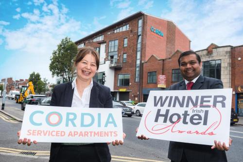 a woman standing next to a man holding a sign at Cordia Serviced Apartments in Belfast