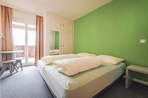 a bedroom with green walls and a bed with pillows at Arosa Mountain Lodge in Arosa