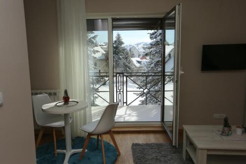a living room with a table and chairs and a large window at Mipet apartmani in Zlatibor