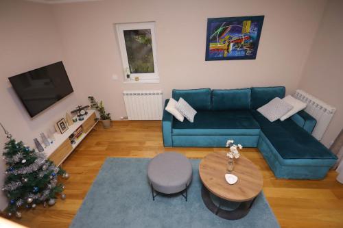 a living room with a blue couch and a christmas tree at Mipet apartmani in Zlatibor
