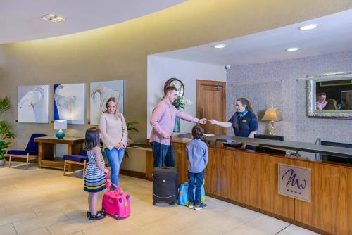un gruppo di persone in piedi nella hall con bagagli di Manor West Hotel & Leisure Club a Tralee
