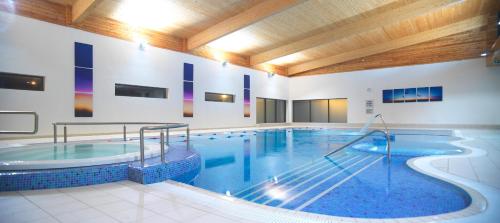 a large swimming pool in a building with a large tub at Manor West Hotel & Leisure Club in Tralee