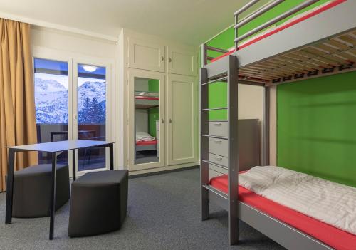 a bedroom with a bunk bed and a desk at Arosa Mountain Lodge in Arosa