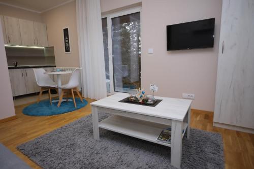 a living room with a white table and a tv at Mipet apartmani in Zlatibor