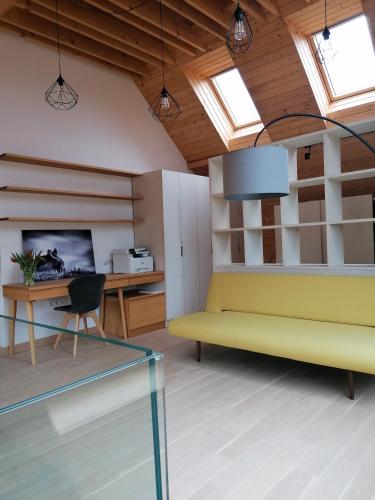a living room with a yellow couch and a desk at Beechtree Property in Izvoare