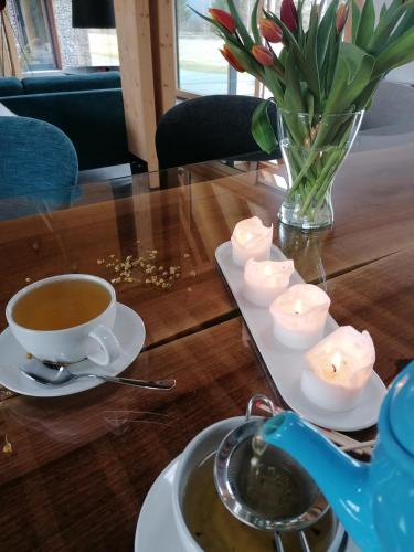 a cup of coffee on a table with candles and a vase of flowers at Beechtree Property in Izvoare