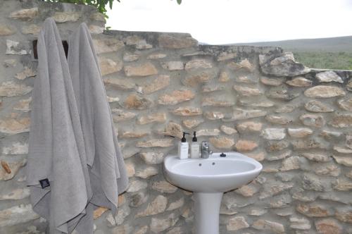 baño con lavabo y pared de piedra en De Hoop Collection - Campsite Rondawels en De Hoop Nature Reserve