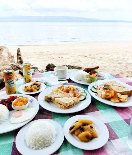 a table with plates of food on the beach at Wuthering Heights Bed & Breakfast by the Sea in Dumaguete