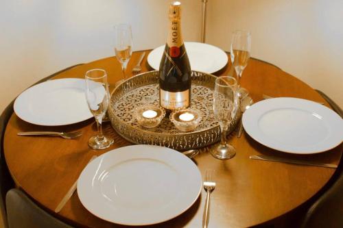 a table with white plates and a bottle of wine at The Old Jail Apartment, Inveraray in Inveraray