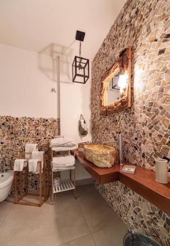 a bathroom with a stone wall with a sink and a mirror at Leonardo Trulli Resort in Locorotondo