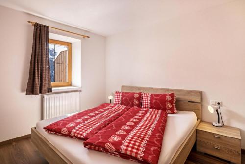 Schlafzimmer mit einem Bett mit roten und weißen Kissen in der Unterkunft Golserhof Kristall in Steinhaus