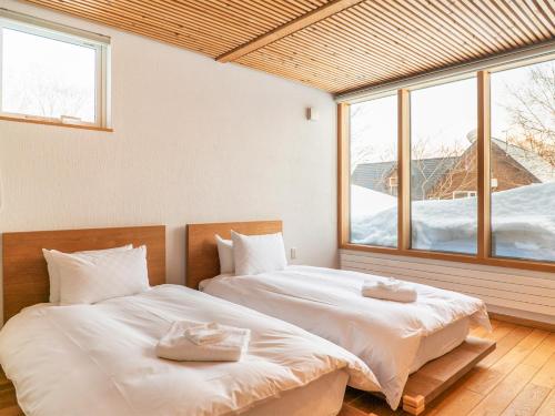 two beds in a room with two windows at Sekka Ni Chalet in Niseko