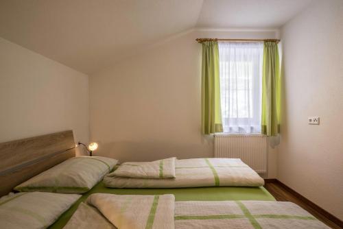 a bedroom with two beds and a window with green curtains at Golserhof Sonne in Cadipietra