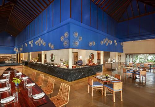 a restaurant with blue walls and wooden tables and chairs at Alila Diwa Goa - A Hyatt Brand in Majorda