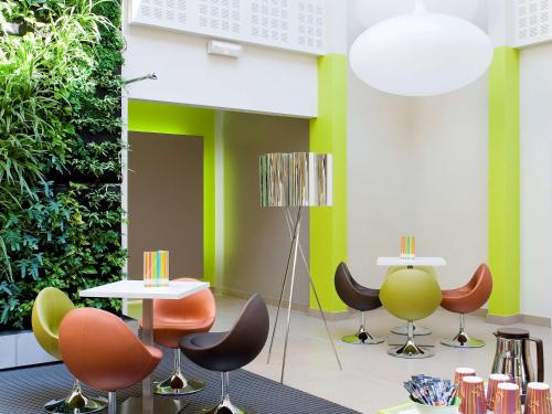 a room with tables and chairs and a green wall at ibis Styles Bordeaux Aéroport in Mérignac