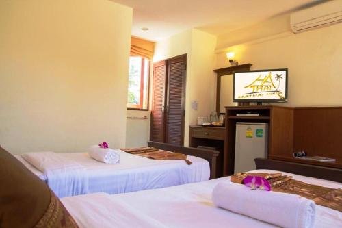a hotel room with two beds and a television at Hathai House in Lamai