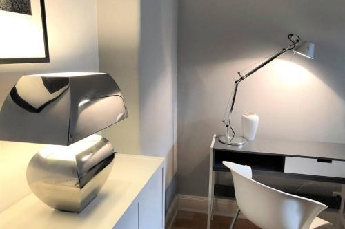a office with a desk with a chair and a lamp at Stadtpark-Domizil - 70 qm, zentral & ruhig in Hamburg