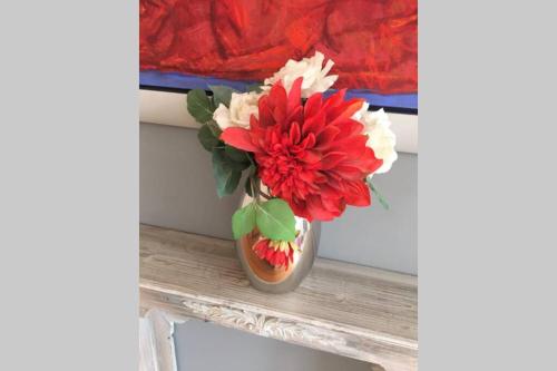 a vase with red and white flowers sitting on a window sill at Stadtpark-Domizil - 70 qm, zentral & ruhig in Hamburg