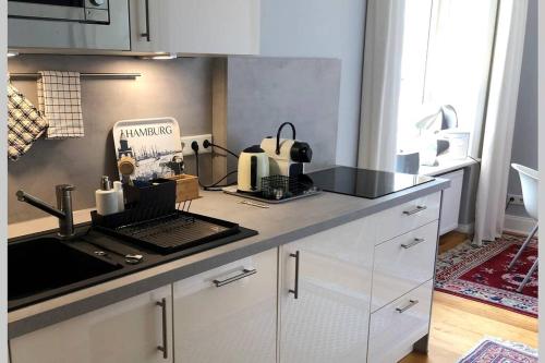 a kitchen with white cabinets and a counter top at Stadtpark-Domizil - 70 qm, zentral & ruhig in Hamburg
