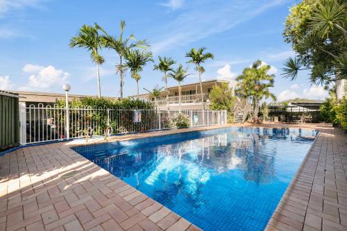 a large blue swimming pool with trees and a building at Gladstone CBD Motel in Gladstone