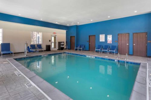 a large swimming pool with blue walls and chairs at Comfort Inn & Suites Euless DFW West in Euless