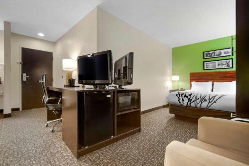 a hotel room with a bed and a flat screen tv at Sleep Inn & Suites Omaha Airport in Omaha