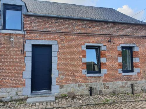 a brick house with a black door and two windows at La Clef des Champs in Potelle
