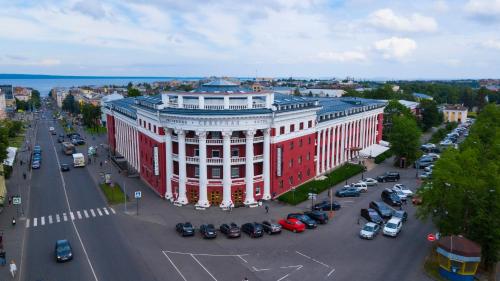 un edificio rojo y blanco con coches estacionados en un estacionamiento en Severnaya Hotel, en Petrozavodsk