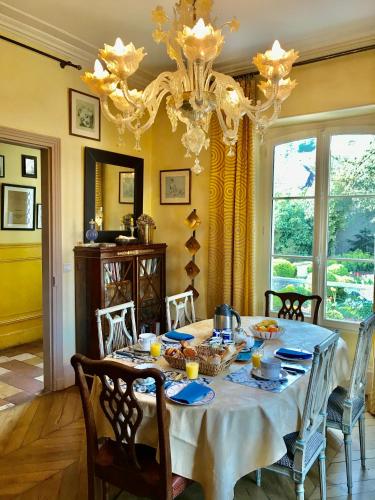 une salle à manger avec une table et un lustre dans l'établissement Le Clos des Princes, à Châtenay-Malabry