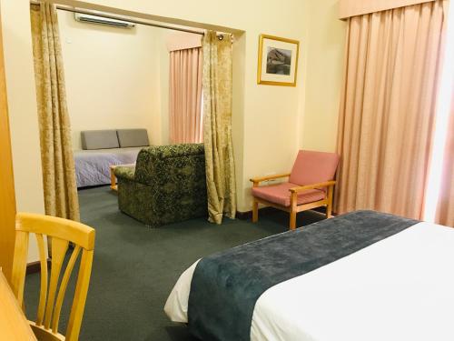 a hotel room with a bed and a chair at Jabal Akhdhar Hotel in Al ‘Aqar