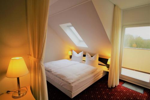ein Schlafzimmer mit einem weißen Bett mit einem Fenster in der Unterkunft Parkhotel Klüschenberg in Plau am See
