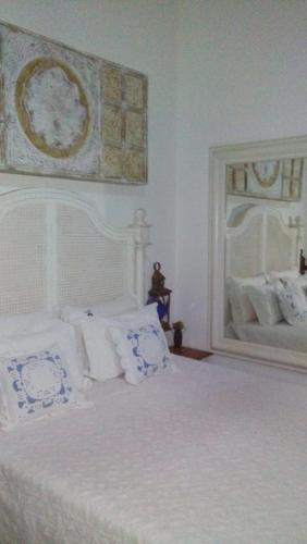 a bedroom with a white bed with pillows and a mirror at Pousada Araujo Bazilio in Tiradentes