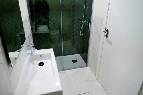 a white bathroom with a shower and a sink at Mid-Atlantic Boutique Hostel in Angra do Heroísmo