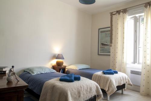 two beds in a bedroom with blue towels on them at FLEUR DE SEL in Saint-Trojan-les-Bains