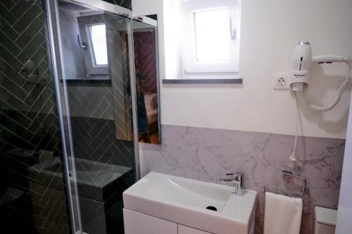 a bathroom with a sink and a glass shower at Mid-Atlantic Boutique Hostel in Angra do Heroísmo