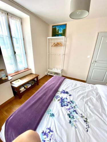 - une chambre avec un lit recouvert d'une couverture violette dans l'établissement La Parisienne des Amognes, à Montigny-aux-Amognes