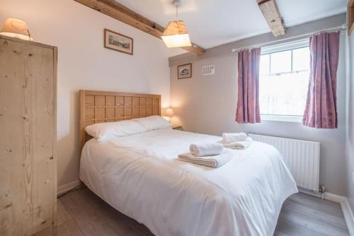1 dormitorio con 1 cama blanca grande y toallas. en Suncatch Corner, Saxmundham en Saxmundham
