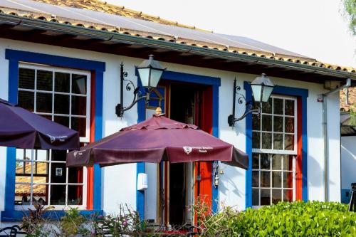 a purple umbrella in front of a blue house at Pousada Araujo Bazilio in Tiradentes