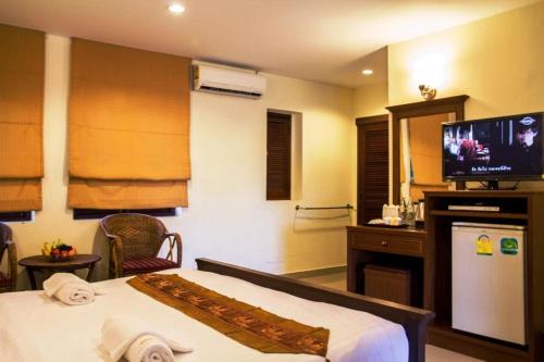 a hotel room with a bed and a flat screen tv at Hathai House in Lamai
