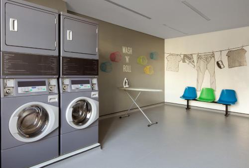 a laundry room with two washing machines and two blue chairs at Rove Dubai Marina in Dubai