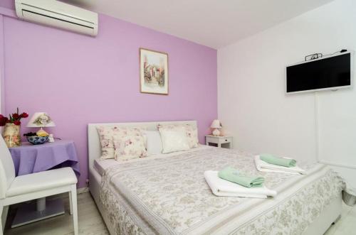 ein Schlafzimmer mit lila Wänden und ein Bett mit Handtüchern in der Unterkunft Guest House Ćuk in Dubrovnik