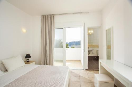 a white bedroom with a white bed and a bathroom at Aethrion Villa Lindos in Líndos