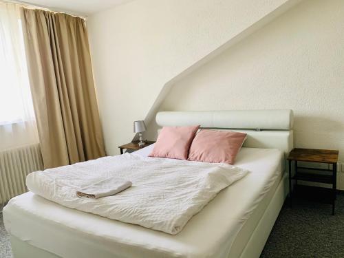 uma cama com duas almofadas cor-de-rosa em cima em Swiss Hotel Krummen Eich Pratteln Free Parking em Pratteln