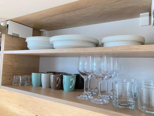 a shelf with wine glasses and bowls on it at Panorama Home Valča in Stará Turá