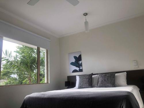 a bedroom with a bed and a large window at Reef Terraces on St Crispins - Villa 2 in Port Douglas