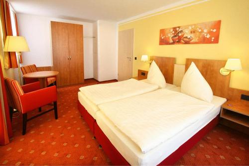 a hotel room with a large bed and a red chair at Hotel Thüringer Hof in Sondershausen