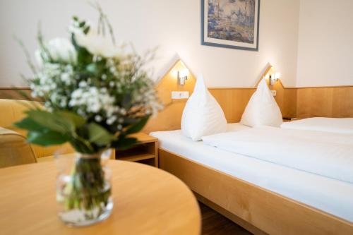 a hotel room with two beds and a vase of flowers on a table at ates Hotel Kehl in Kehl am Rhein