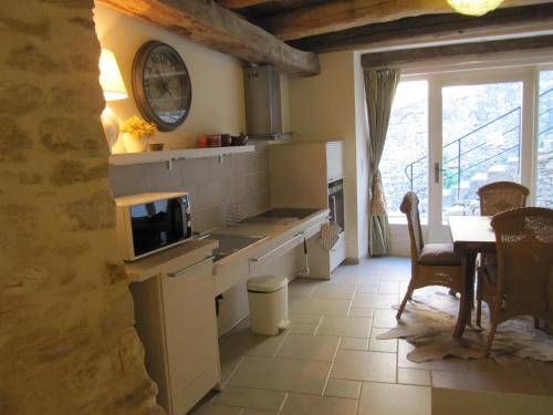 cocina con mesa y reloj en la pared en Clarberg - Gîte, en Saint-André-de-Roquepertuis