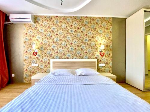 a bedroom with a large bed with a floral wall at ApartPoltava Світлі та просторі двокімнатні апартаменти в новобудові, закритий паркінг , ЦЕНТР МІСТА, банківський ЧЕК in Poltava